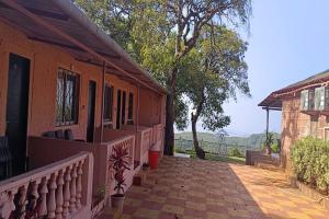 a house with a porch and a balcony at Dwarka Lawns Cottages in Mahabaleshwar