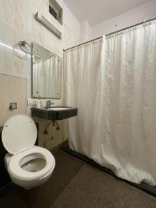 a bathroom with a white shower curtain and a toilet at Svaruchi Inn in New Delhi