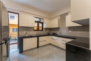 a large kitchen with white cabinets and black counter tops at Luxury Apartments with Swimming Pool near Candolim Beach in Candolim