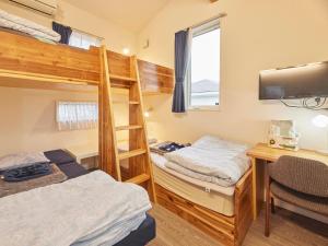 a bedroom with two bunk beds and a desk at Itosima Guesthouse TOMO in Itoshima