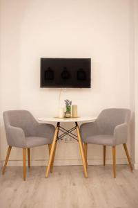 twee stoelen en een tafel met een tv aan de muur bij Luxury Ultra Central in Sibiu