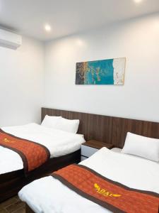 Habitación con 3 camas y una pintura en la pared. en Adal Motel en Kiến An