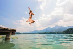 法克湖畔杜罗博拉赫Seeblick Faaker See的跳进码头进入水体的女人