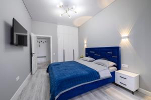 a bedroom with a blue bed and a tv at Апартаменты на Гагарина in Almaty