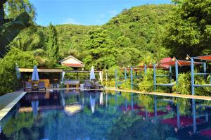 una piscina con sedie e ombrelloni di fronte a una montagna di Villa 'The Blue House' - Qbungalows a Kep
