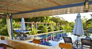 a patio with a pool with chairs and umbrellas at Villa 'The Blue House' - Qbungalows in Kep