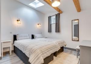 a bedroom with two beds and a mirror at The Barn at the Grange in Hawes