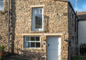 a stone house with a white door and a window at The Barn at the Grange in Hawes