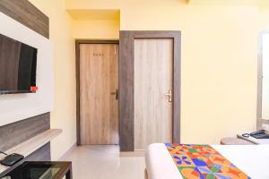 a room with a door and a bed and a television at FabHotel Bypass View in Kolkata