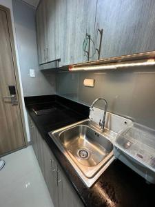 a kitchen with a stainless steel sink and wooden cabinets at Mall of Asia MOA S Residences , IKEA Pasay in Manila