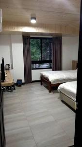 a bedroom with two beds and a desk and a window at Beautiful Guest House II in Chin-sha