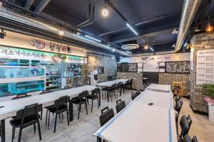 um restaurante com mesas e cadeiras num quarto em Jin Arirang Hostel em Yeosu