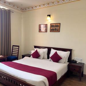 um quarto com uma cama grande e almofadas vermelhas e brancas em Laxmi Niwas em Jaipur