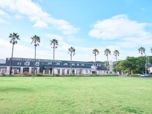 un bâtiment avec des palmiers en face d'un champ dans l'établissement Rakuten STAY HOUSE x WILL STYLE Miyazaki Aoshima, à Miyazaki