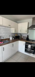 a kitchen with white cabinets and a black oven at Provis Wharf Homestay in Buckinghamshire