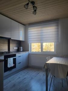 a kitchen with white cabinets and a table with a window at Poilsis dviems in Šiauliai