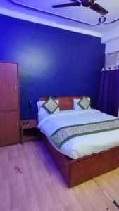 een slaapkamer met een bed met een blauwe muur bij Hotel The Grace Near Delhi Airport in New Delhi