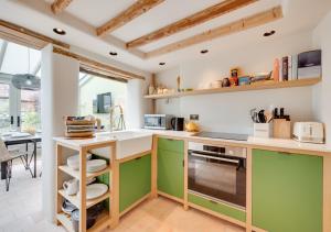 a kitchen with green and white cabinets and a table at No.1 Baileygate Cottages in Castle Acre