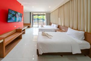 two beds in a room with a red wall at Nongnooch Garden Pattaya Resort in Ban Nong Chap Tao