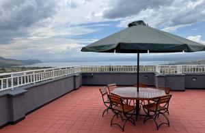a table and chairs with an umbrella on a roof at Naka Executive Suites With Balcony, Amazing Lake Nakuru View, GYM in Nakuru