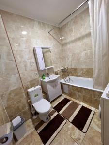 een badkamer met een toilet, een wastafel en een bad bij Апартаменты напротив спорткомплекса Алматы Арена 81-29 in Alma-Ata