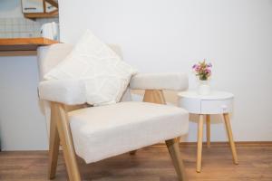 a white chair with a white pillow and a side table at Cozy City Apartments in center K28 in Vienna