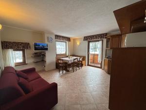 a living room with a red couch and a table at Chalet Bucaneve in Santa Caterina Valfurva