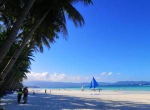 a group of people on a beach with a sail boat at Boracay Coco Huts in Boracay