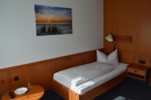 ein kleines Bett in einem Zimmer mit einem Tisch in der Unterkunft Gasthof-Pension Fränkische Schweiz Obertrubach in Obertrubach