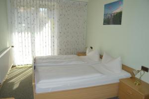 Cama blanca en habitación con ventana en Gasthof-Pension Fränkische Schweiz Obertrubach, en Obertrubach