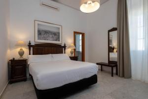 a bedroom with a large white bed and a mirror at Hotel Tugasa Casa Palacio Medina Sidonia in Medina Sidonia