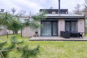 ein Haus mit einer Holzterrasse im Hof in der Unterkunft Life's a Beach Cottage in Palanga