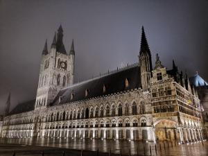 un gran edificio con una torre de reloj por la noche en Old Saxo, en Ypres