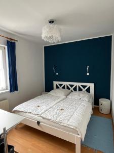 a bedroom with a white bed and a blue wall at Apartment Gartenstrasse 3 in Ostseebad Sellin