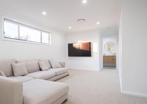 a white living room with a couch and a tv at Elegance and Style in Wagga Wagga