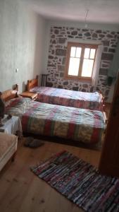 a bedroom with two beds and a stone wall at Stone house cottage in Sígrion