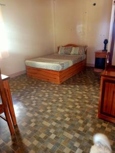 een slaapkamer met een bed en een tegelvloer bij Smylen Homestay in Maria