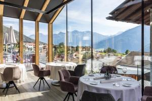 a restaurant with tables and chairs and a view of mountains at Hotel Weisses Kreuz in Malles Venosta