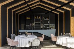 um restaurante com duas mesas e cadeiras e um bar em Hotel Weisses Kreuz em Malles Venosta