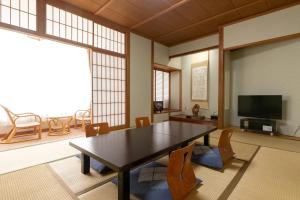 a dining room with a table and chairs and a tv at ホテル晴山 in Chikuma