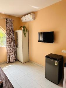 a room with a small refrigerator and a tv on the wall at Poetry: Pvt Studio in Koregaon Park . AC WiFi SmartTv in Pune