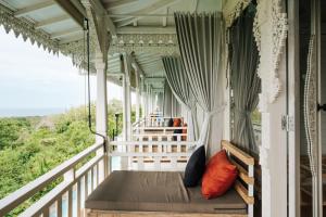 a porch with a bed on a house at Mambo Hill Resort in Nusa Penida