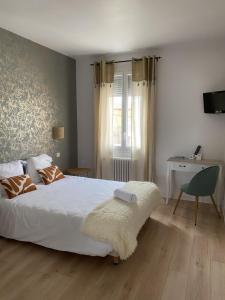 a bedroom with a large white bed and a desk at Hôtel Aux Vendanges de Bourgogne in Paray-le-Monial