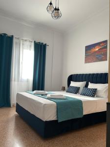 Schlafzimmer mit einem großen Bett und blauen Vorhängen in der Unterkunft Technopolis Luxury Apartments in Athen