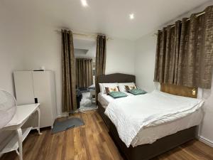 1 dormitorio con 1 cama, escritorio y ventanas en 4TH Studio Flat a Family Luxury London Home A Fully Equipped and furnished Studio With a King Size Bed And a Futon-Sofa Bed A Baby Cot A Kitchenette With a Private Toilet and Bath a Garden For up to 4 Guests and Free Parking, en Lewisham