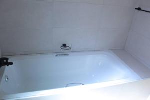 a white tub in a bathroom with a white tile wall at Gaborone 1 bed suburban bliss in Gaborone