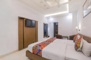 a bedroom with a bed and a tv on the wall at FabHotel Prime The Continental in Lucknow