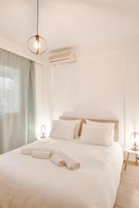 a white bed with two towels on top of it at Sugar Blue - Apartments on the beach in Áyios Vasílios