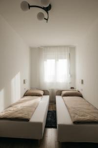 Duas camas num quarto branco com uma janela em SEVEN em Vinkovci