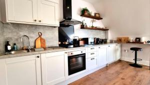 una cocina con armarios blancos y fregadero en Top floor 1BR apartment central Matlock, en Matlock